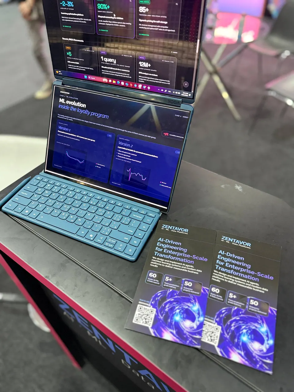 A laptop at the stand showing Zentavor case studies, next to printed brochures